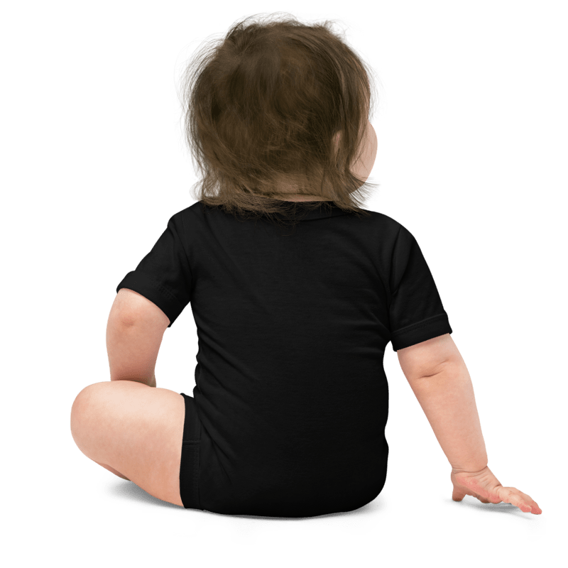 Child wearing a black onesie sitting on a white background