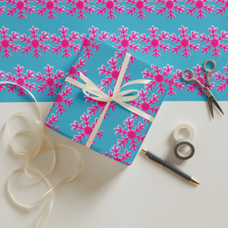 Gift box with pink snowflakes on blue background, ribbon, scissors, and tape.