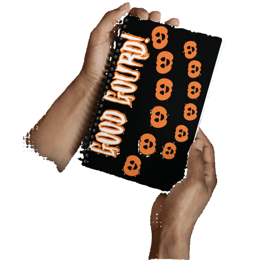 Person holding a notebook with Halloween-themed design featuring orange skulls and 'Good Boudri!' text.