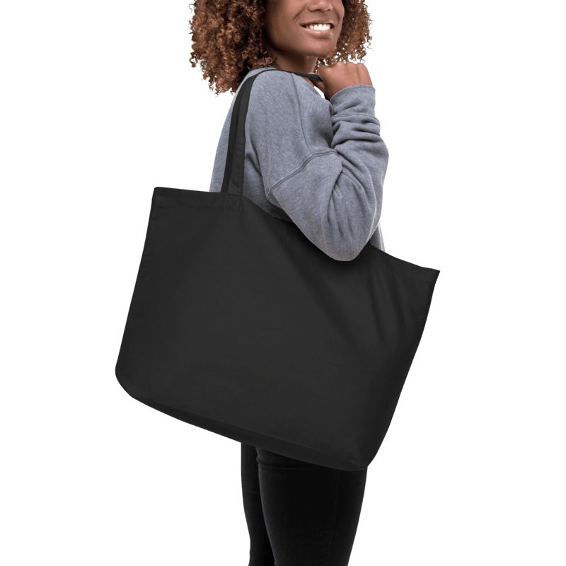 Person holding a black tote bag against a white background