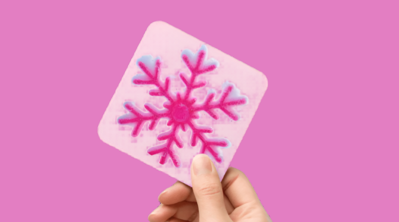 Hand holding a pink card with a snowflake design on a white background