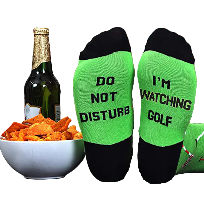 Green socks with text 'Do Not Disturb' and 'I'm Watching Golf' next to a bottle and bowl of chips on a couch.