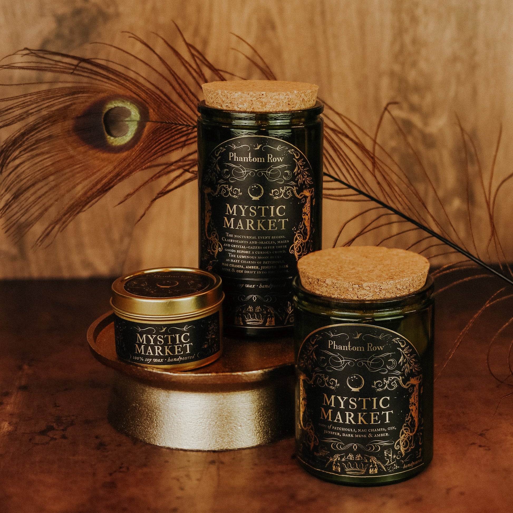 Three jars labeled 'Mystic Market' by Phantom Row on a wooden surface with peacock feathers.