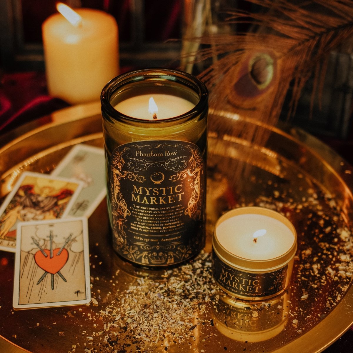 Two candles labeled 'Mystic Market' on a reflective surface with tarot cards in the background.