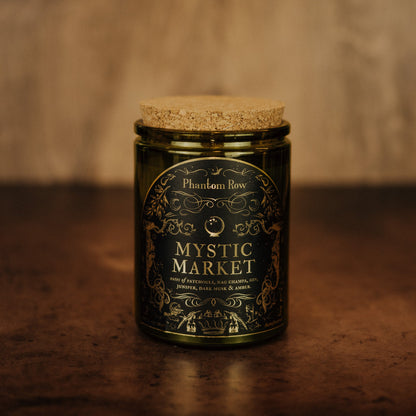 Mystic Market candle in a green jar with a cork lid on a brown surface.