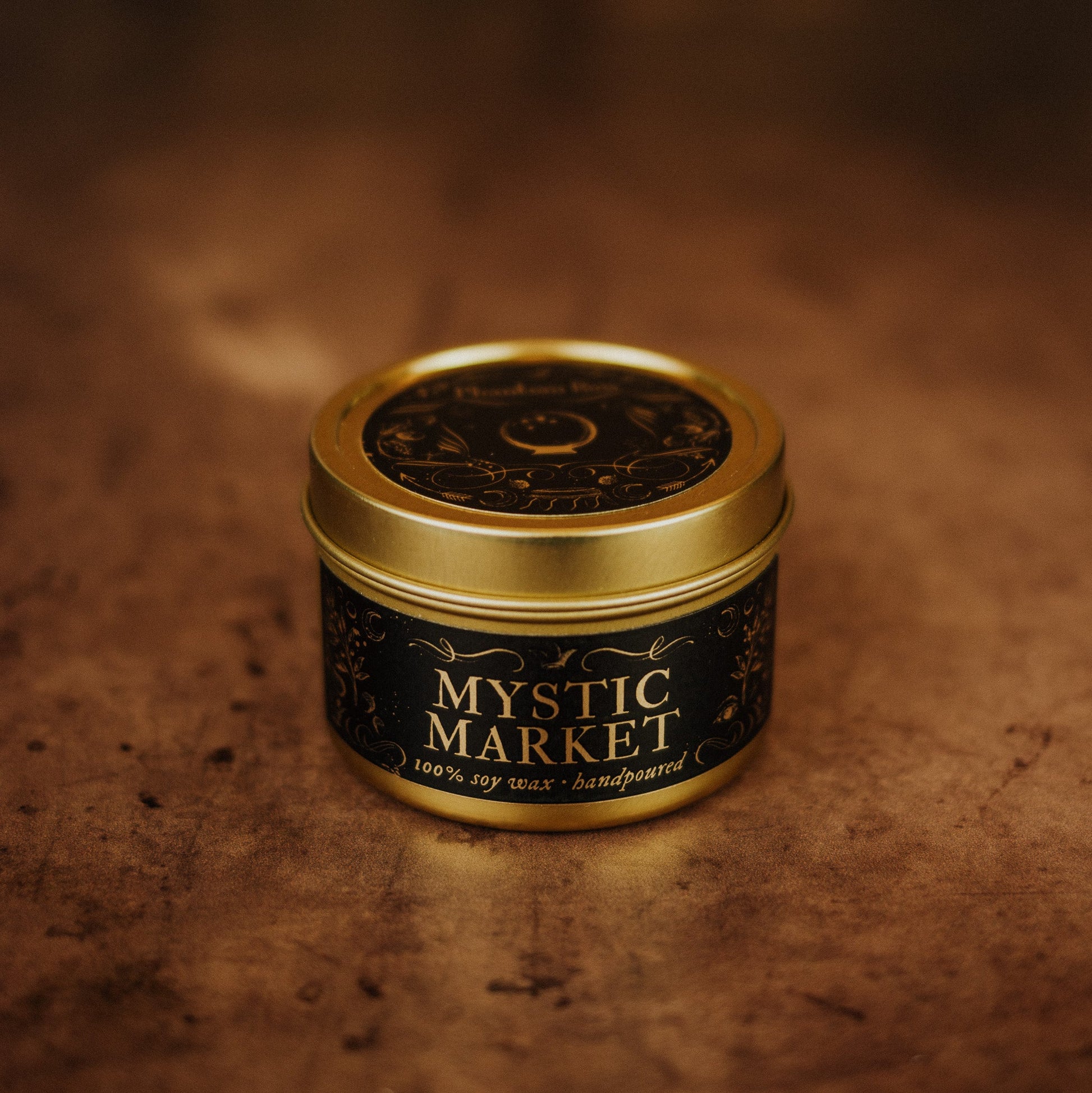 Mystic Market candle in a gold tin on a textured brown background