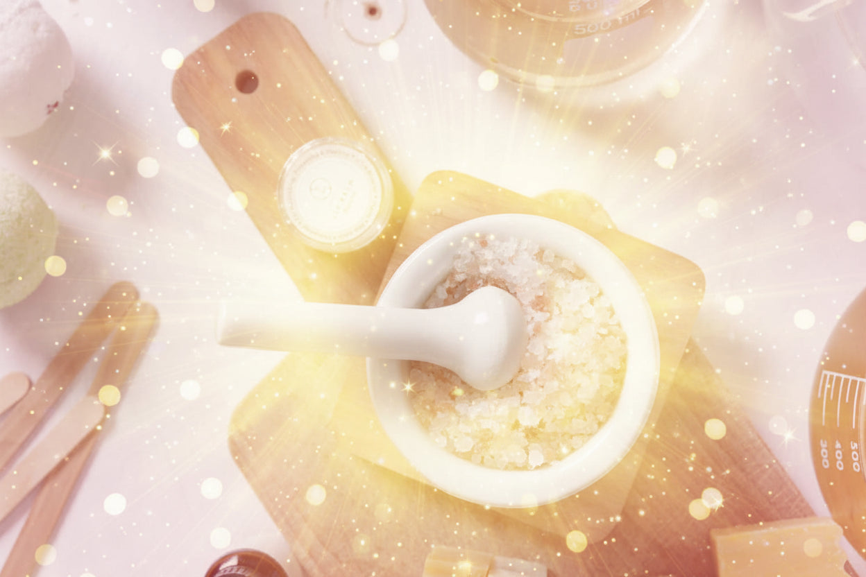 Mortar and pestle with pink Himalayan salt on a wooden board with various skincare products.