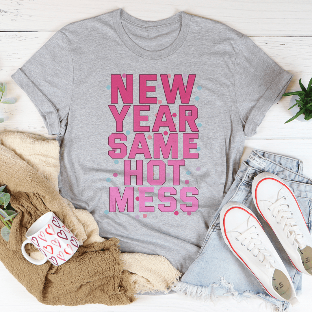 Gray t-shirt with pink text 'NEW YEAR SAME HOT MESS' on a white surface with casual items.