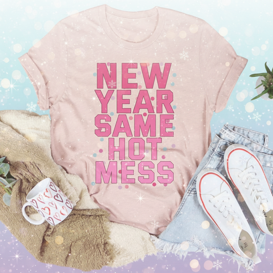 Pink t-shirt with 'New Year Same Hot Mess' text on a white surface with accessories.