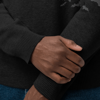 Close-up of a person wearing a black sweater with their hands clasped together.