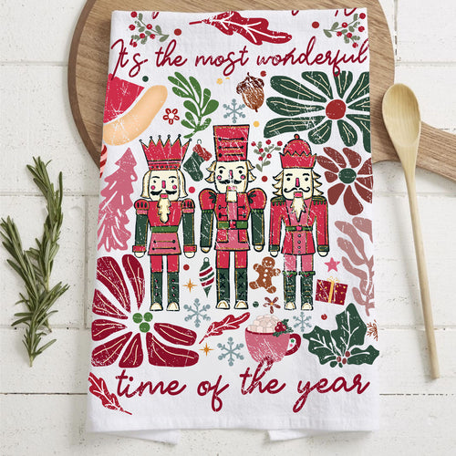 Decorative towel with Christmas-themed design featuring nutcrackers and floral elements on a wooden surface.
