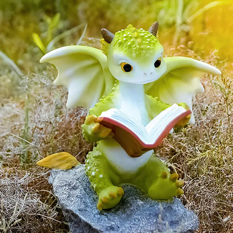 Green dragon figurine reading a book on a stone in a natural setting