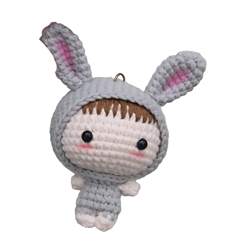 Crocheted character wearing a bunny costume held by a hand on a textured gray background
