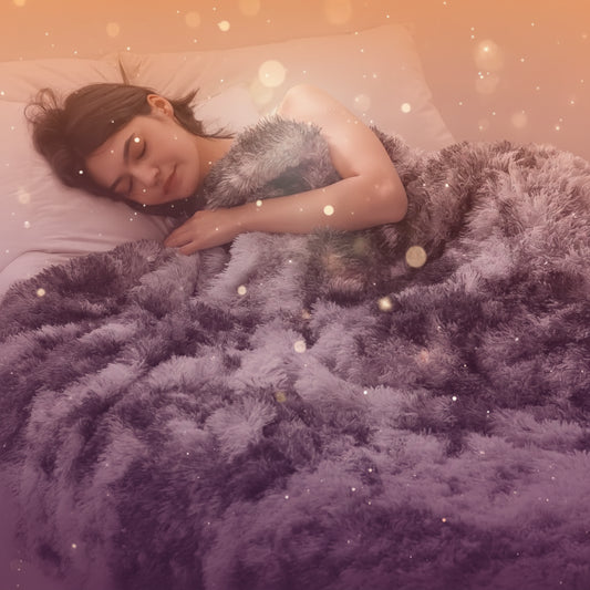 Woman lying on a bed under a fluffy gray blanket