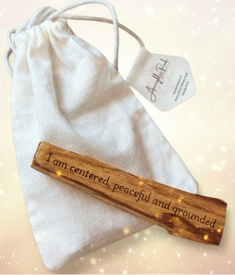 Wooden pendant with engraved text on a white drawstring bag with a tag, on a beige surface.