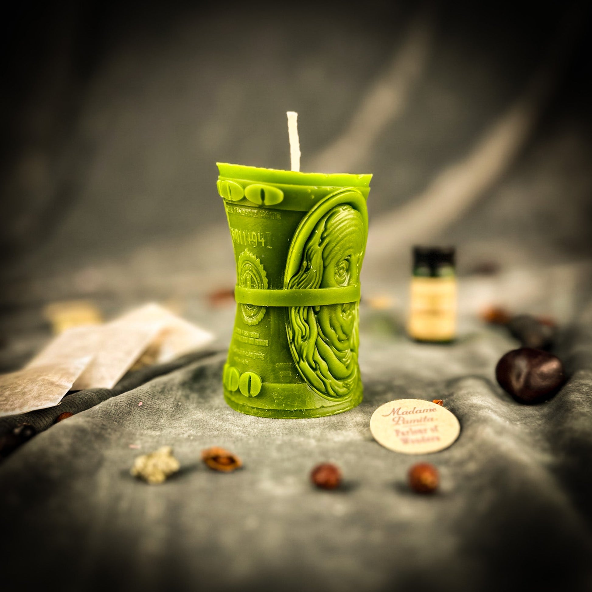 Green candle shaped like a dollar bill on a dark surface with blurred background
