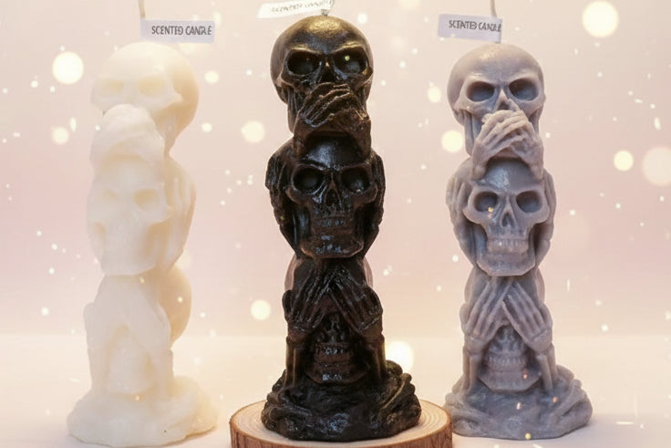 Three skull-shaped candles with labels on a white surface.