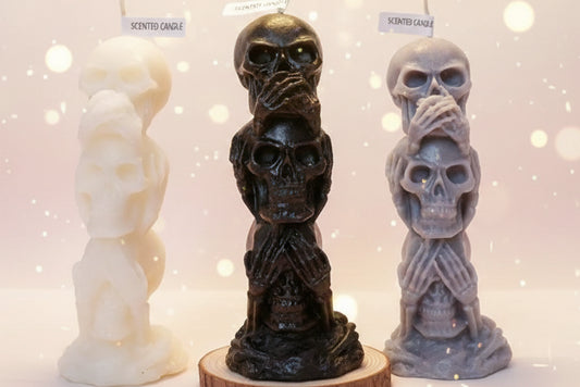 Three skull-shaped candles with labels on a white surface.