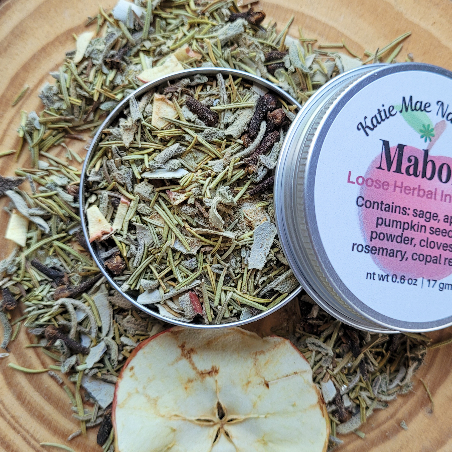 Loose herbal ingredients with a container labeled 'Katie Mae N' on a wooden surface.