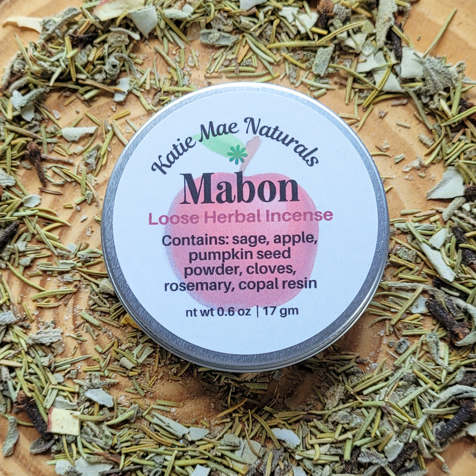 Katie Mae Naturals Mabon Loose Herbal Incense container surrounded by dried herbs.