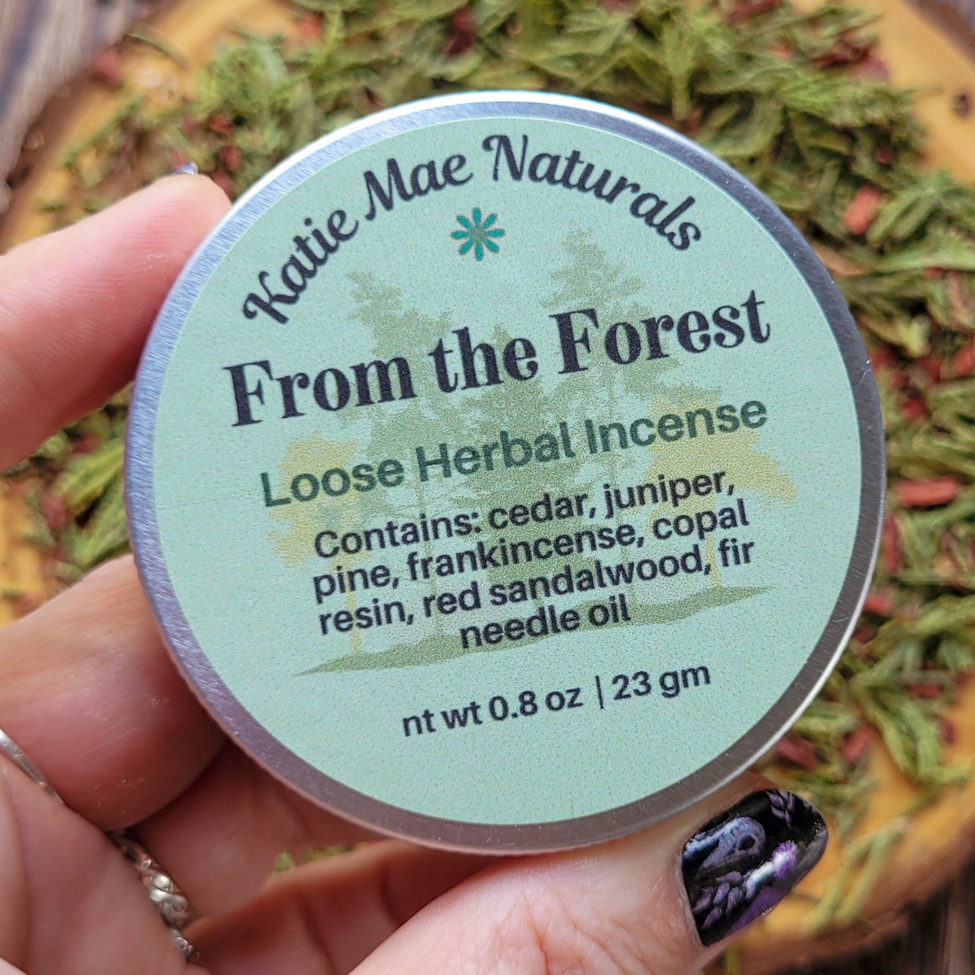 Katie Mae Naturals Loose Herbal Incense container held by a hand with a blurred natural background