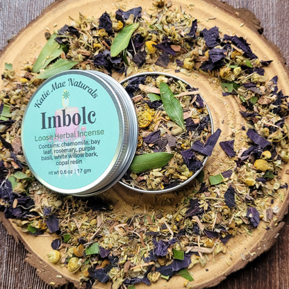 Katie Mac Naturals Imbolc Loose Herbal Incense on a wooden surface with dried herbs.