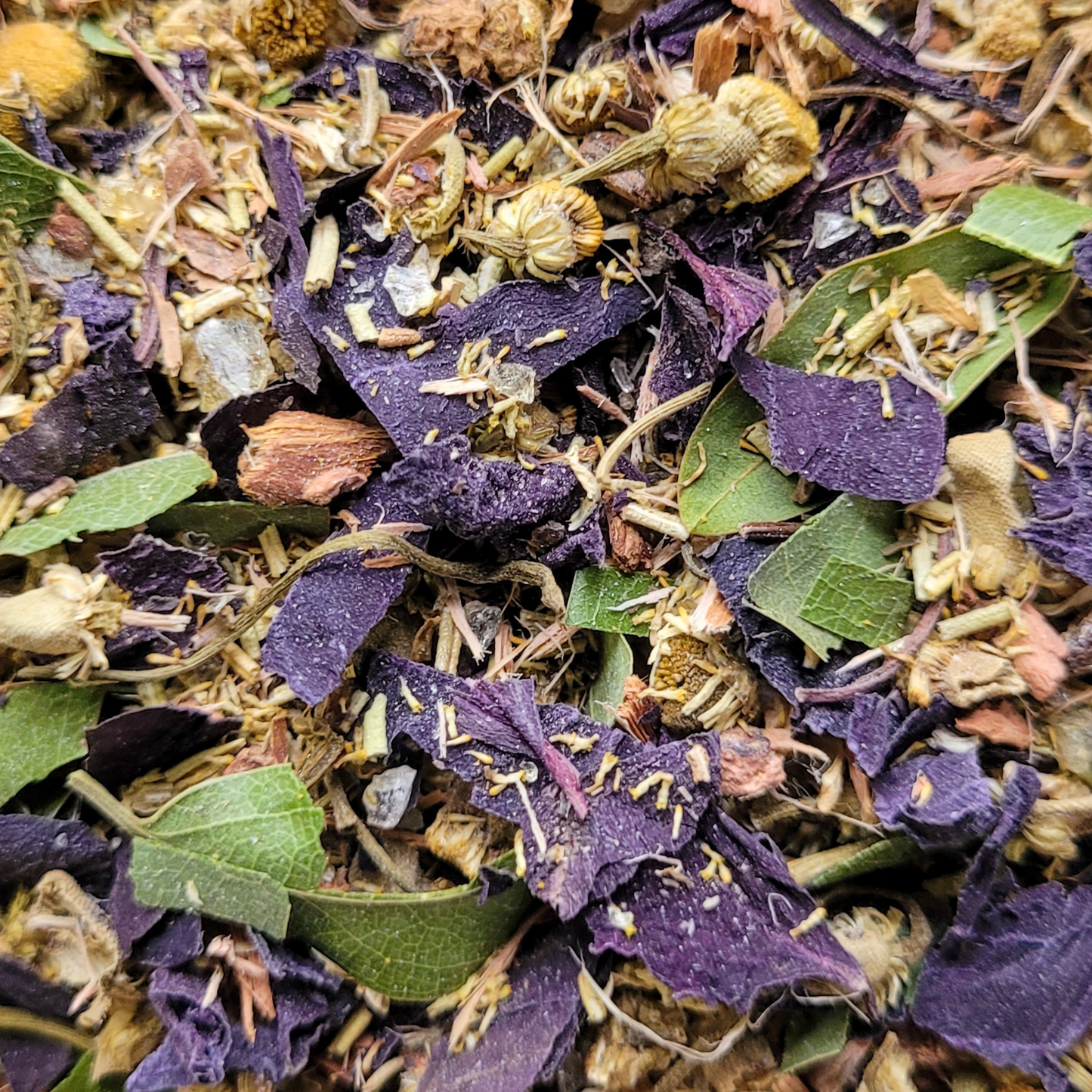 Close-up of a mix of dried herbs and flowers with purple and green leaves.