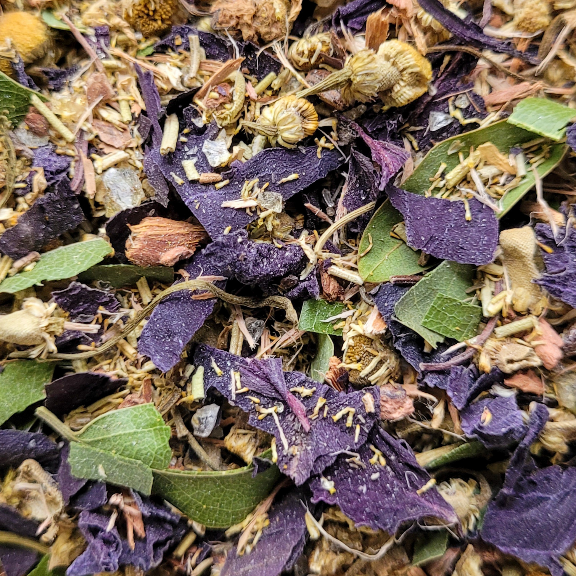 Close-up of a mix of dried herbs and flowers with purple and green leaves.