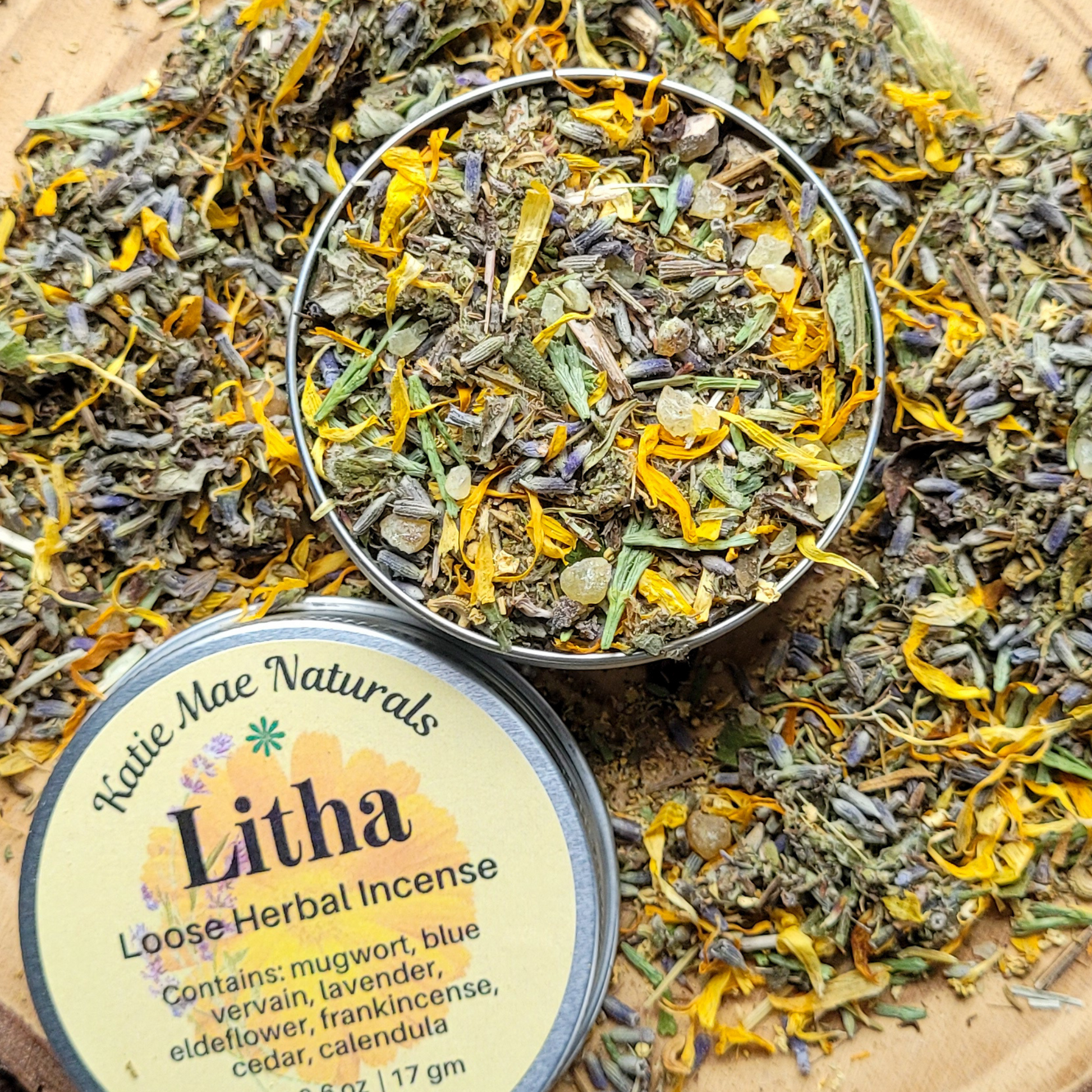 Loose herbal incense in a tin with 'Katie Mae Naturals' label on a wooden surface.