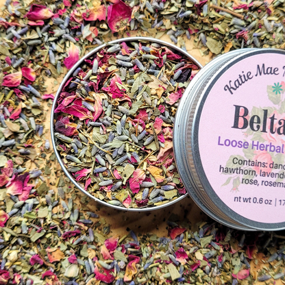 Loose herbal tea in a tin with a label on a bed of dried herbs