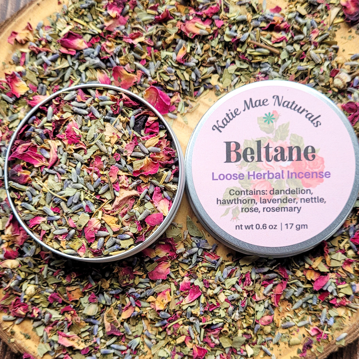 Beltane loose herbal incense from Katie Mae Naturals on a wooden board with dried herbs.