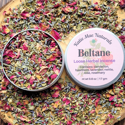 Beltane loose herbal incense from Katie Mae Naturals on a wooden board with dried herbs.