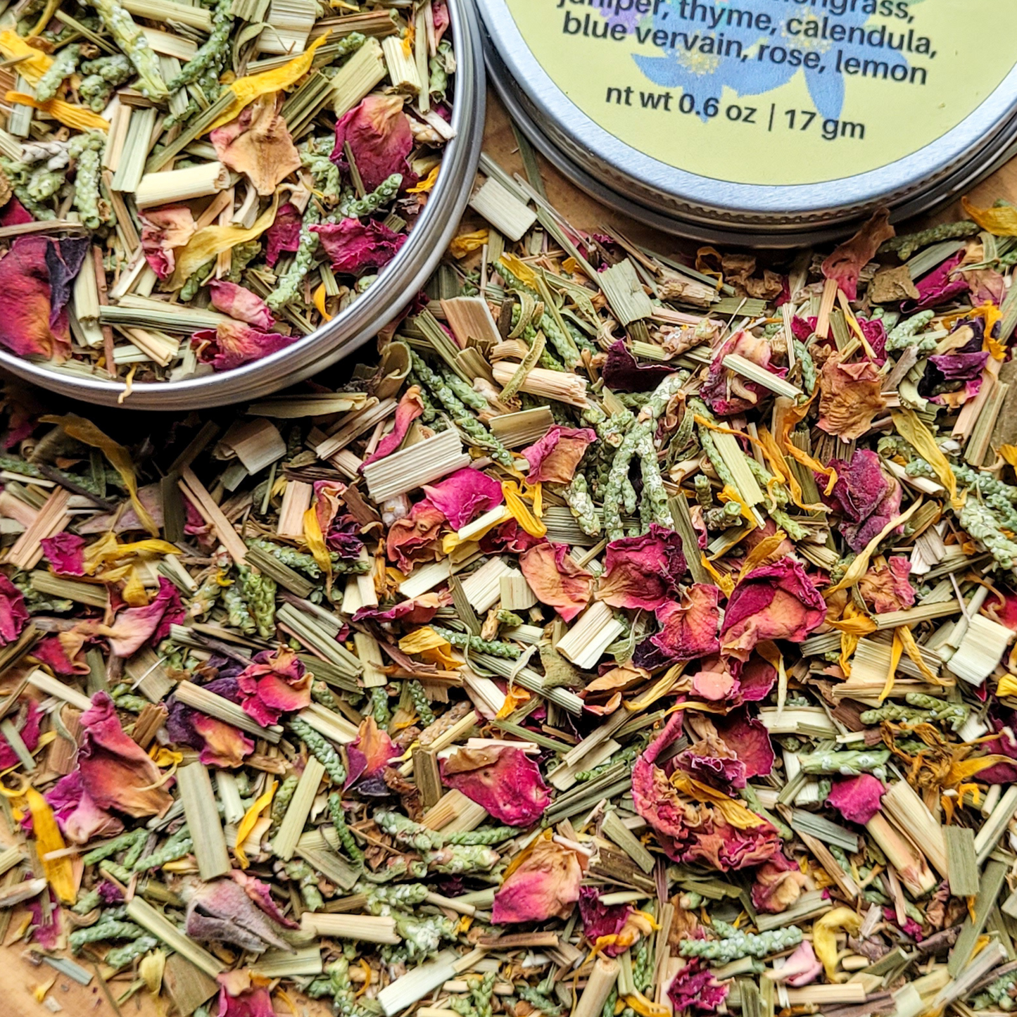 Herbal mixtures in tins with visible ingredients on a wooden surface