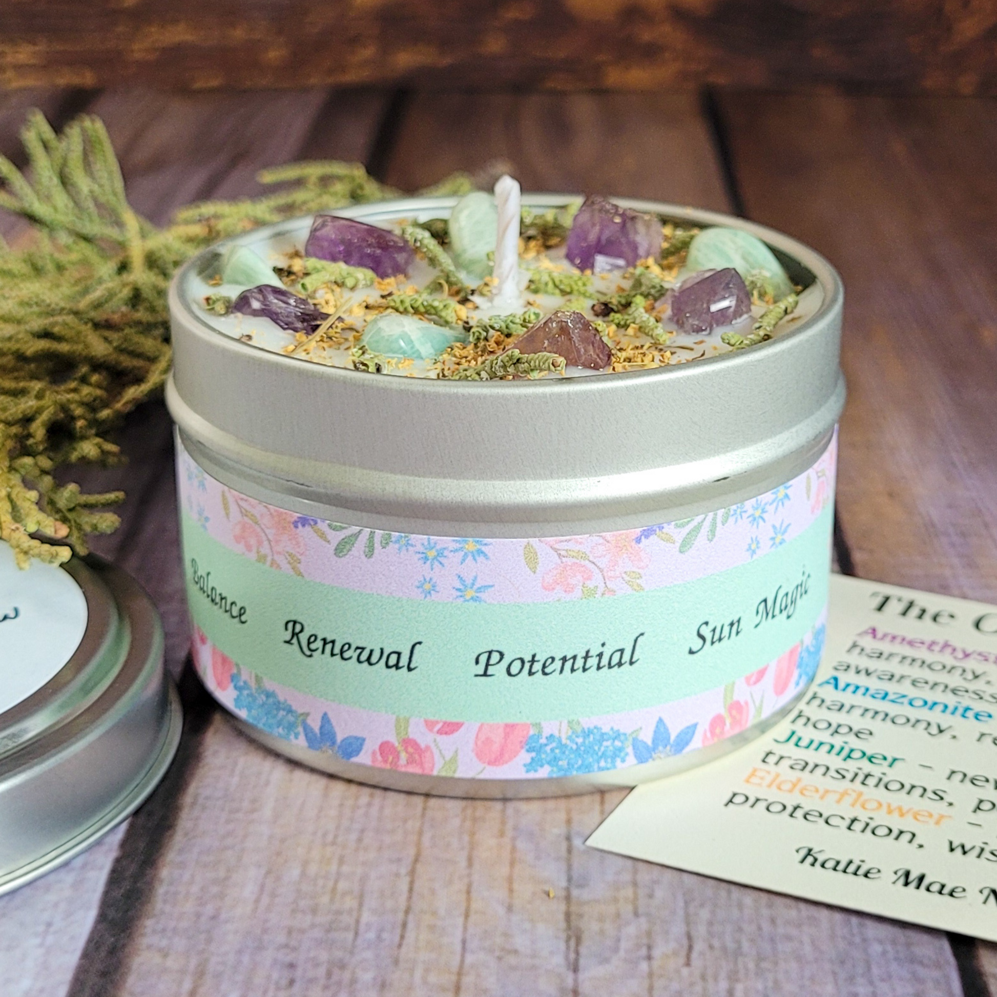 Candle in a tin with decorative label on a wooden surface