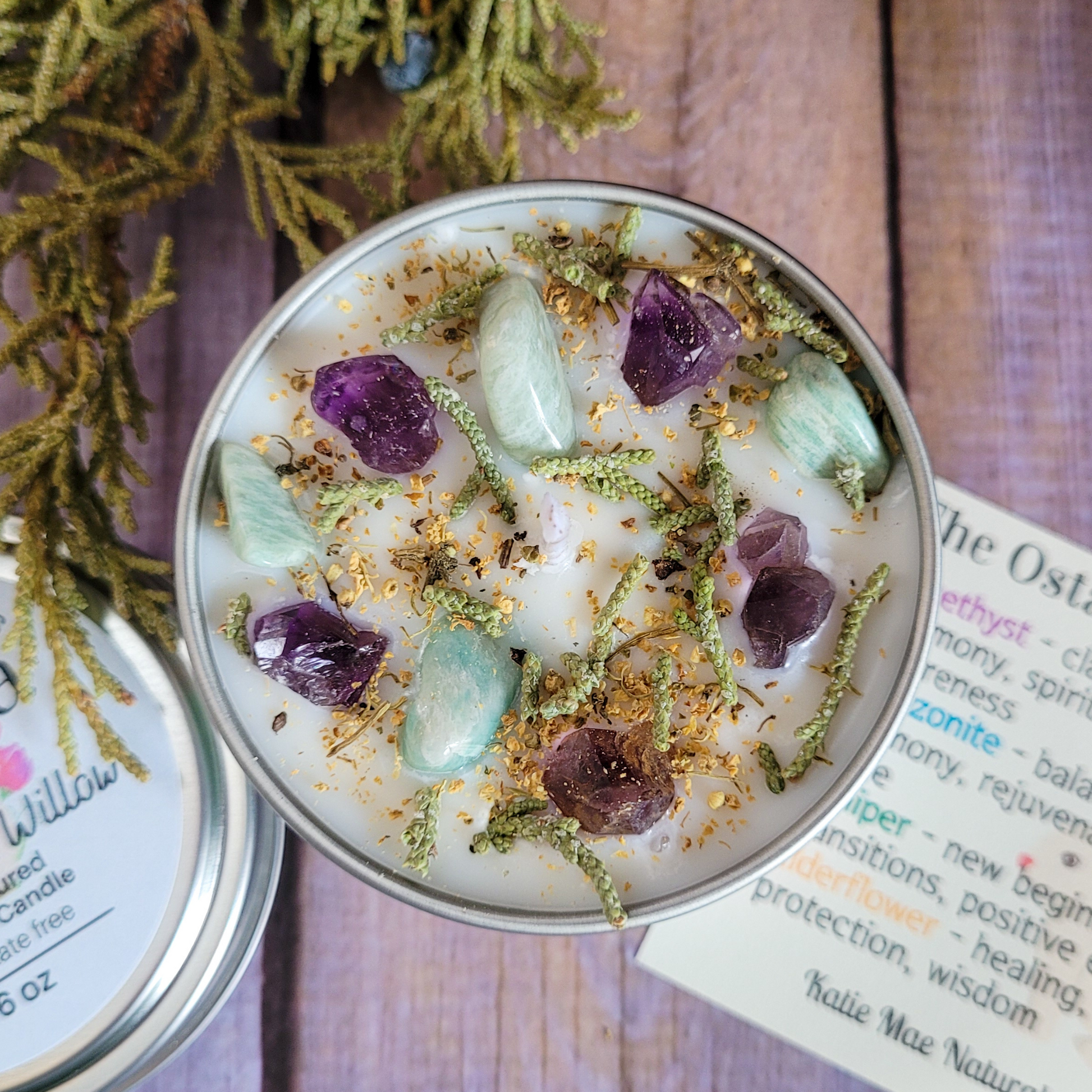 Candle with crystals and herbs on a wooden surface