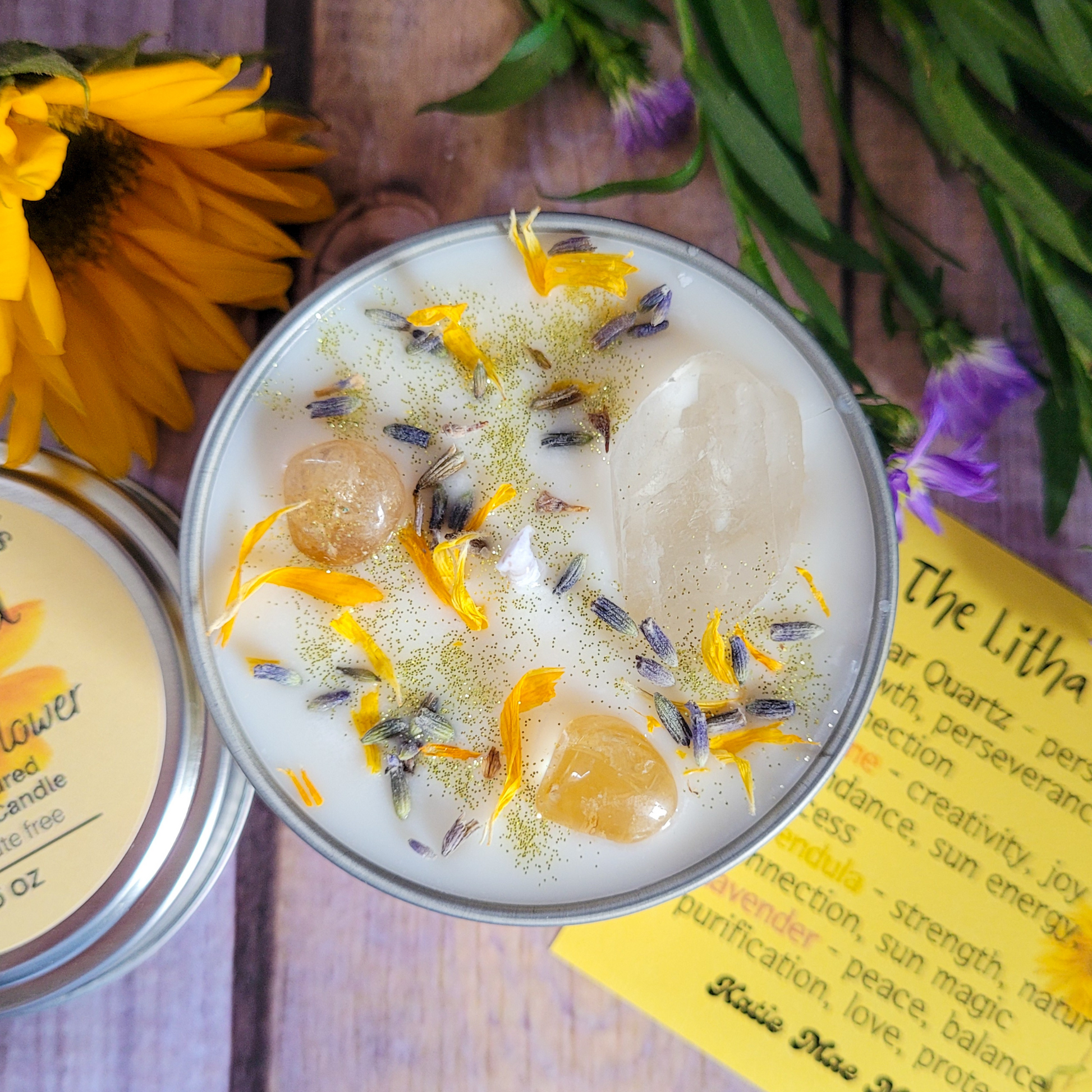 Candle with natural elements on a wooden surface with flowers and text