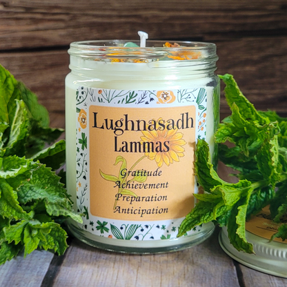 Candle in a glass jar with a decorative label surrounded by green leaves on a wooden surface
