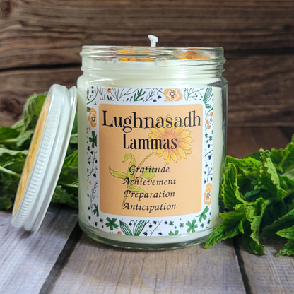 Candle in a glass jar with a decorative label on a wooden surface with greenery.