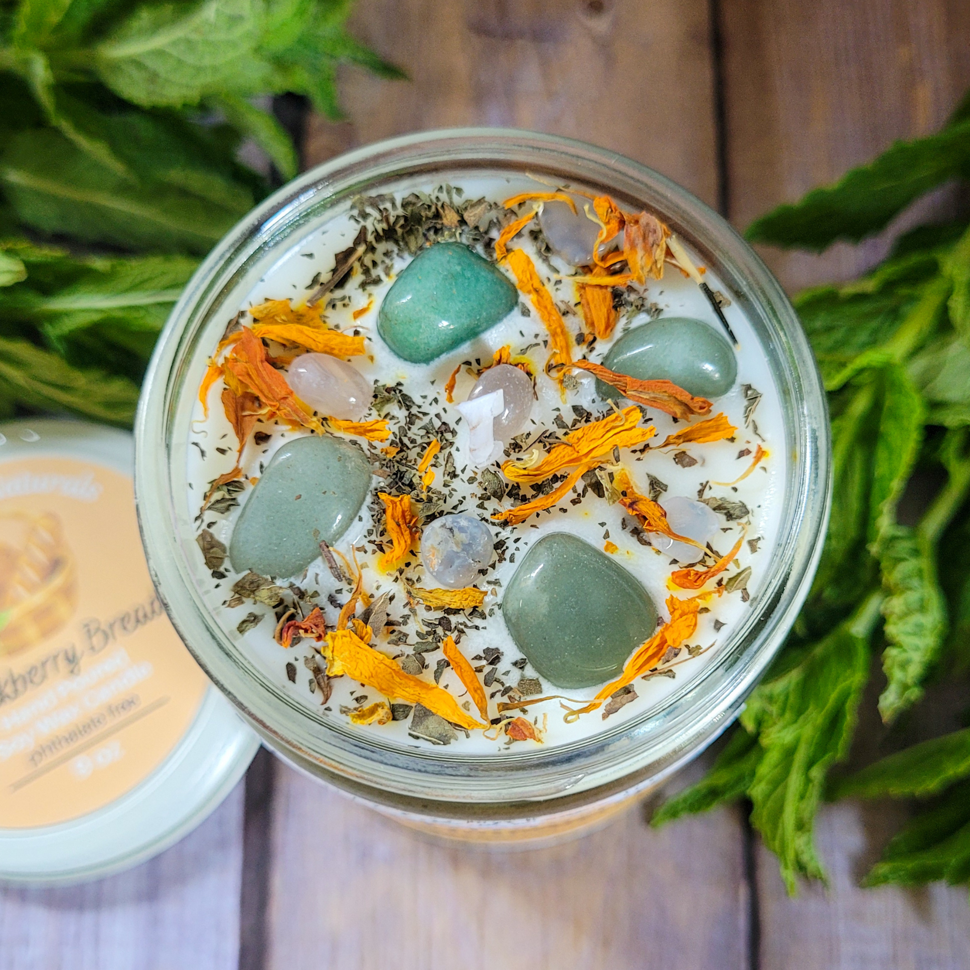 Glass jar with decorative stones and herbs on a wooden surface