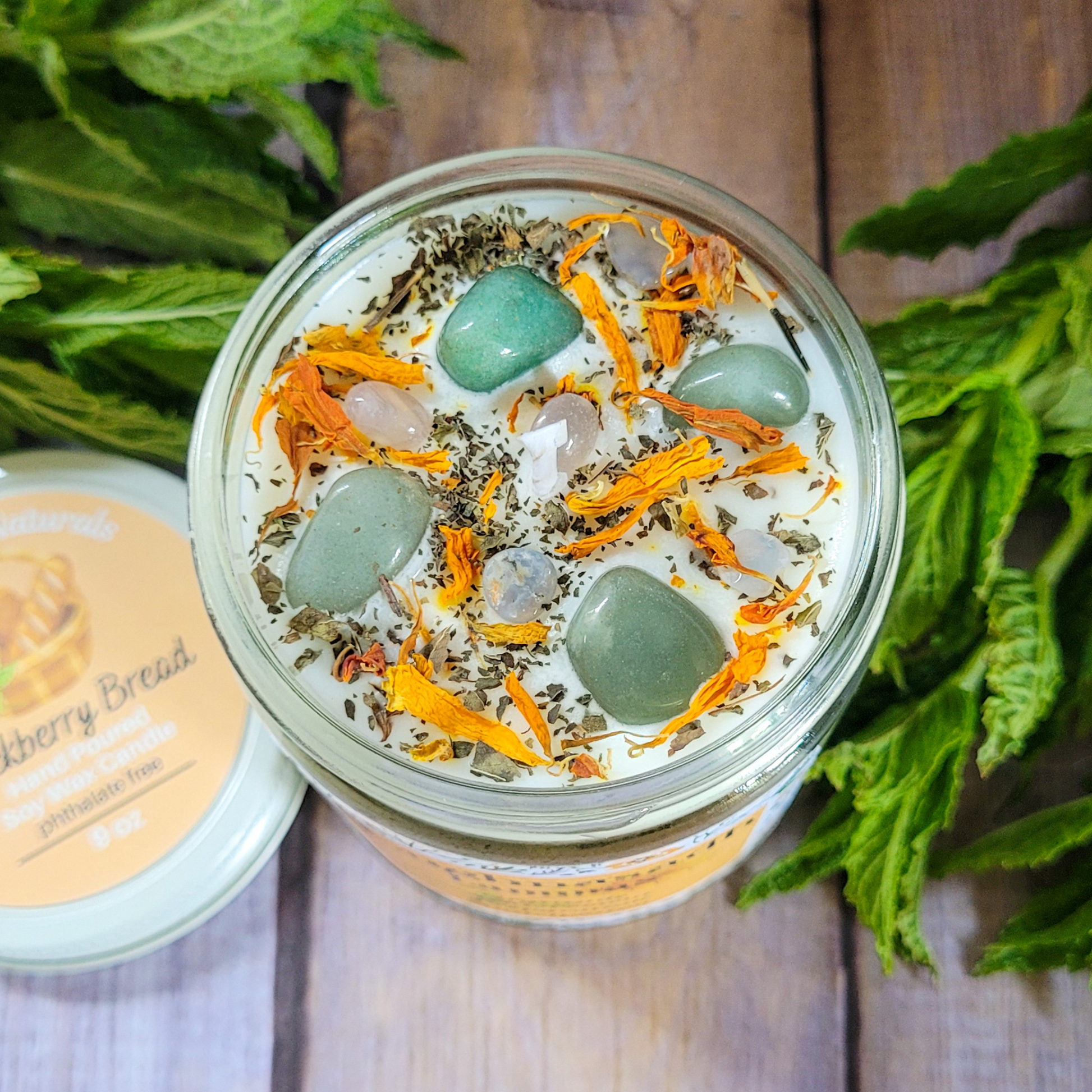 Jar of candle with herbs and stones on a wooden surface