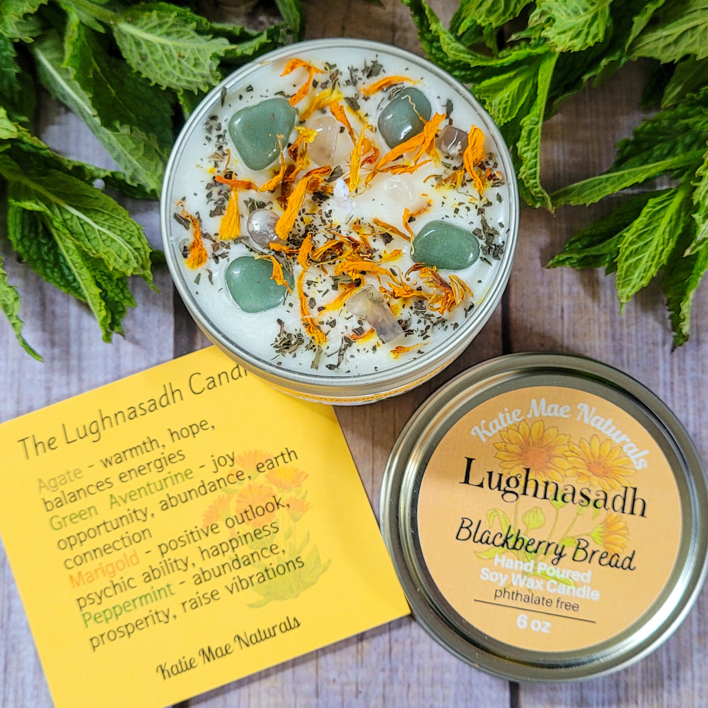 Two candles with decorative elements and a label on a wooden surface with greenery.