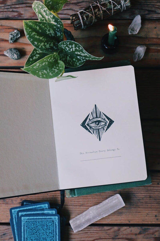 Notebook with eye design on a wooden surface with plants and crystals