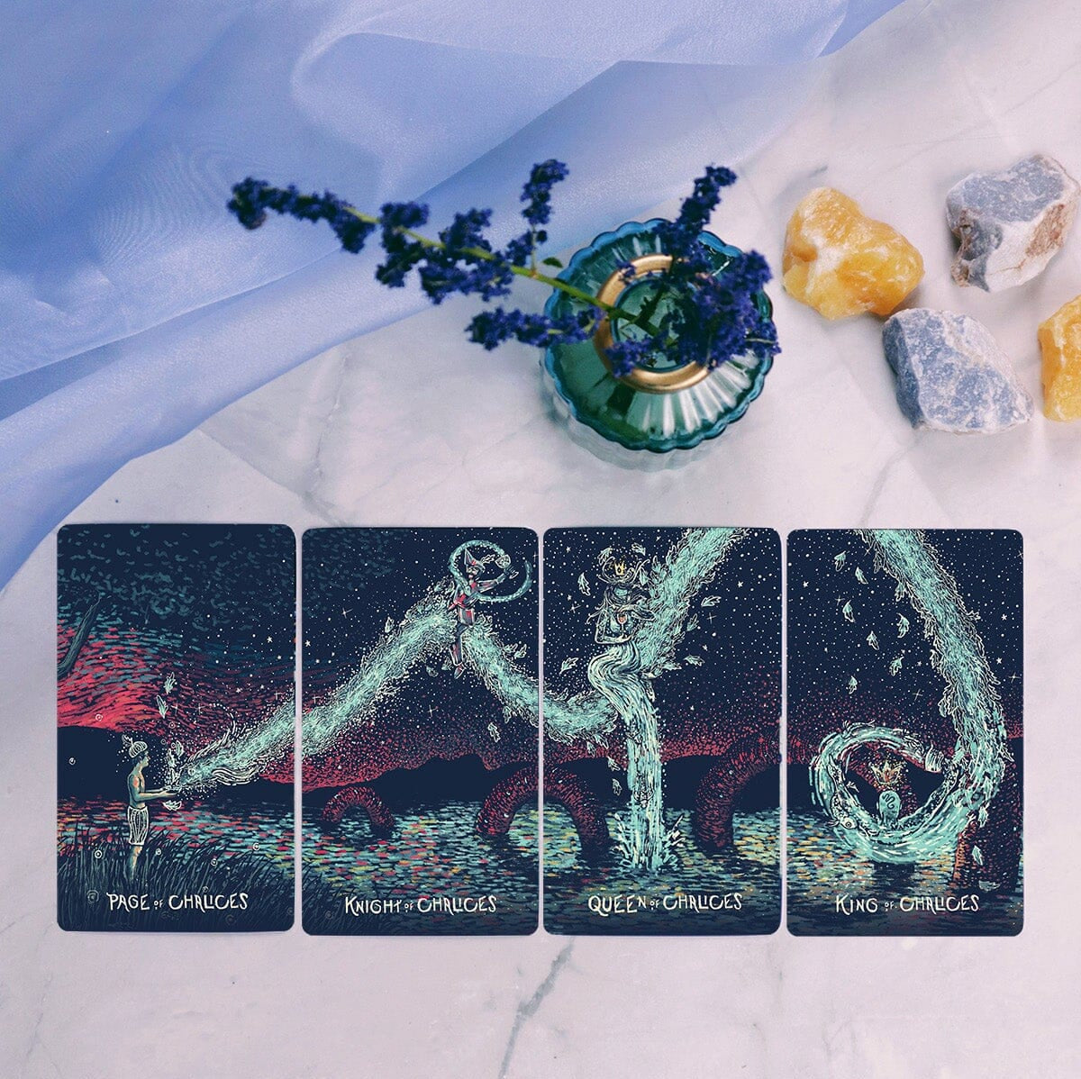 Four tarot cards on a textured surface with stones and a plant.