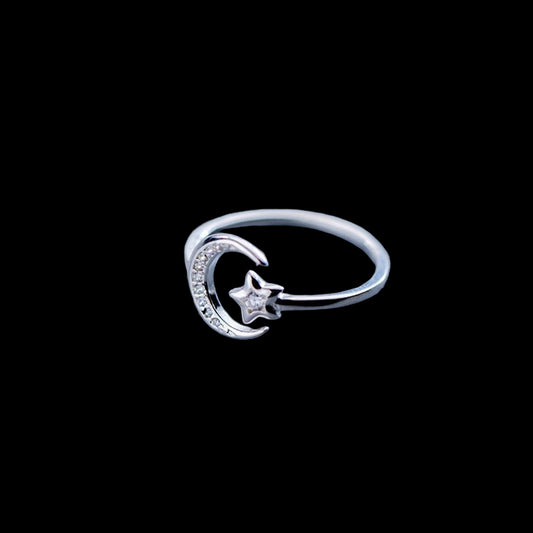 Silver ring with moon and star design on a light gray background