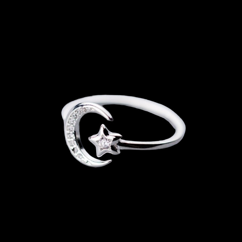 Silver ring with moon and star design on a light gray background