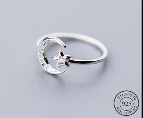 Silver ring with moon and star design on a light gray background