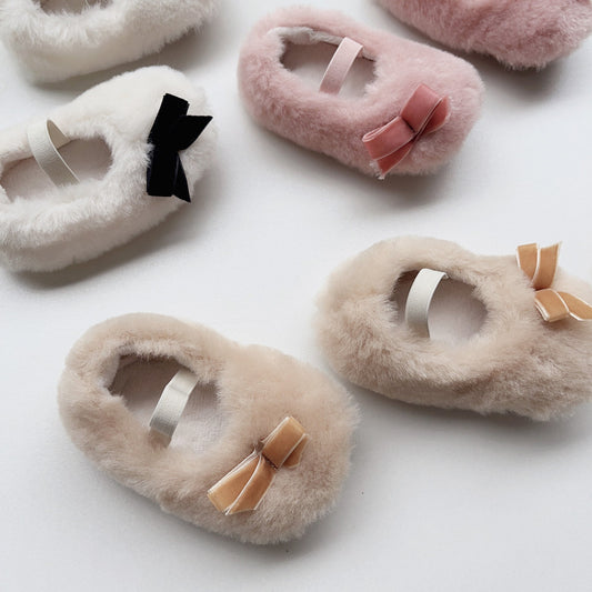 Fluffy slippers with colorful bows on a white background