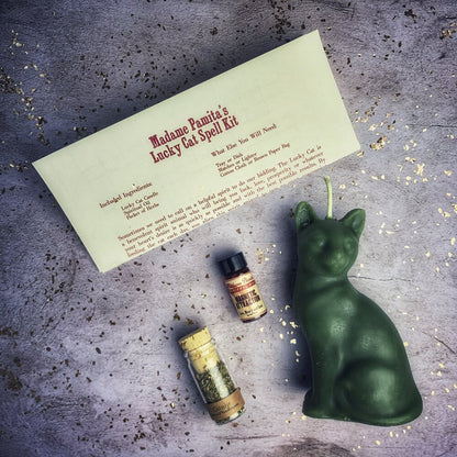 Green cat-shaped candle with spellbook and bottles on a textured surface