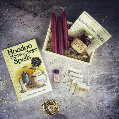Hoodoo Honey and Sugar Spells book with honey jar, candles, and other items on a textured surface