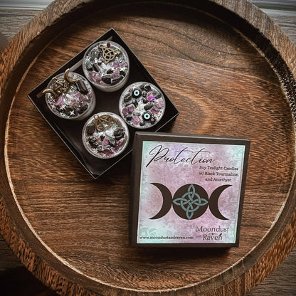 A boxed set of four moon phase soy candles in a black tray, shown next to the product card on a round wooden tray. The card reads 'Protection Soy Twilight Candles w/ black Traumatization and Ambition' and shows the brand name 'Moondust Rituals'.